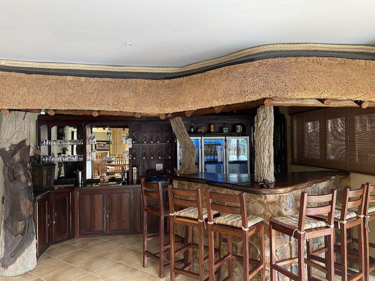 The built in bar, with its stone clad counter under a thatched canopy