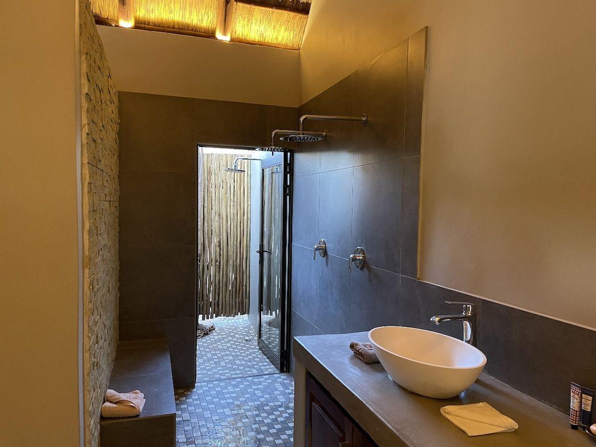 A bathroom with a vessel basin, opening to an outdoor shower